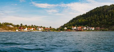 İsveç 'in batı kıyısındaki takımada üzerindeki küçük bir adada bulunan Idyllic İsveç Yazlık Evi. Sakin ve güneşli bir yaz günüydü. Suya yakın yerleşim alanının manzarası vardı..