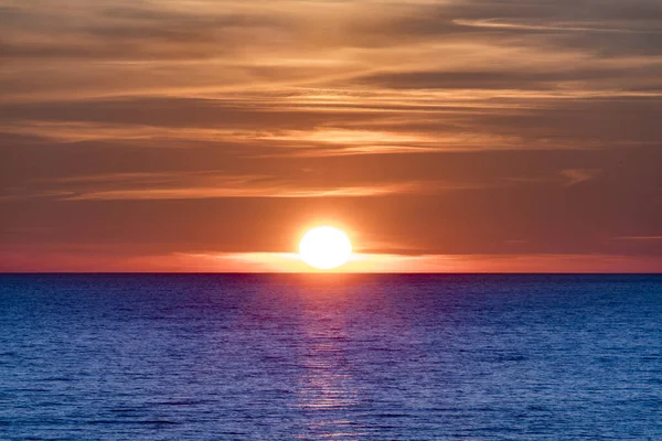 Orange Sun set over blue ocean. Beautiful Setting sun at beach Tylosand Halmstad, one of Swedens most popular beaches.