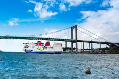 GOTHENBURG, SwEDEN - 30 Haziran 2019: Gothenburg Stena Line gemisinin Göteborg sahnesi Alvsborgs Köprüsü arka planında İsveç bayrağıyla Gothenburg limanından ayrılıyor - Göteborg 'da seyahat eden İkonik Sahne.