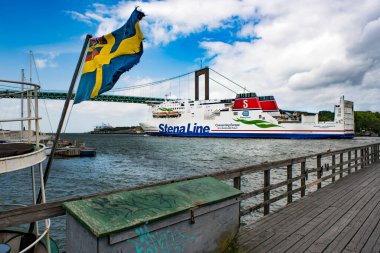 GOTHENBURG, SwEDEN - 30 Haziran 2019: Gothenburg Stena Line gemisinin Göteborg sahnesi Alvsborgs Köprüsü arka planında İsveç bayrağıyla Gothenburg limanından ayrılıyor - Göteborg 'da seyahat eden İkonik Sahne.