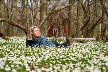 Doğada bir kadın, Anemone çiçeğinin çiçek tarhında yatıyor.