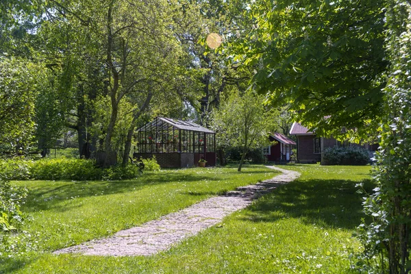 Kas in de tuin met gebogen stenen pad of tegels — Stockfoto