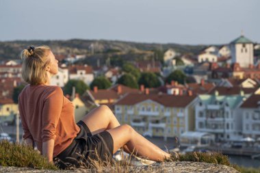 Gülümseyen Kafkasyalı Kadın Marstrand Köyü 'nün üzerinde günbatımının tadını çıkarıyor..