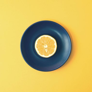 Minimalist bir konseptte, kare arkaplanlı bir tabakta limon meyvesi dilimi..