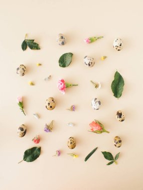 Easter concept, with eggs, and colorful spring flowers, roses, green leaves, arranged in a square on a pastel background. flat lay.