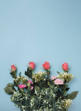 Pembe güllerle, pembe karanfillerle ve pastel mavi arka planda küçük beyaz çiçeklerle romantik bahar çiçek aranjmanı. Minimum konsept. düz yat.