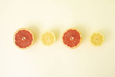 Yaz kompozisyonu. Taze limon ve kırmızı greyfurt dilimlenmiş ve sıraya konmuş. Pastel ve bej arkaplana karşı en düşük bileşim.