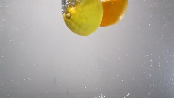 Citron et orange tombent dans l'eau au ralenti 