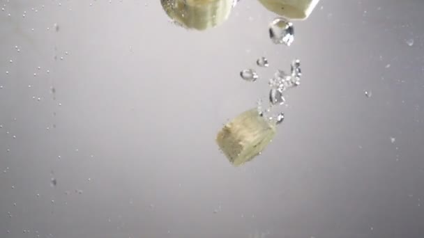 Stukjes banaan druppels onder water. — Stockvideo