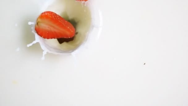 Trozos de fresa caen en la leche — Vídeos de Stock