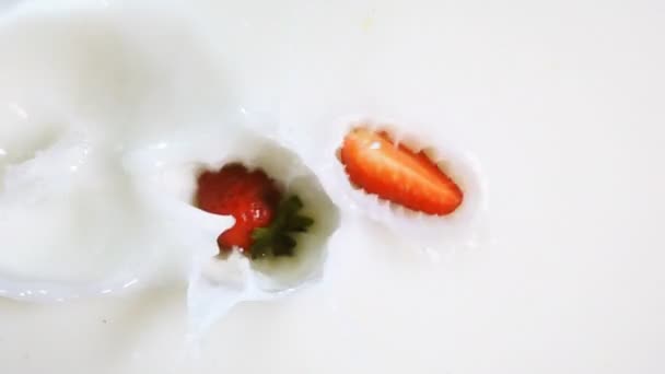 Pieces of strawberry drop into the milk — Stock Video