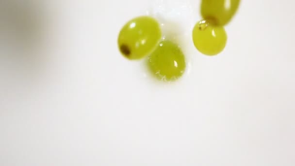 Baies vertes de raisins tombant dans le lait 