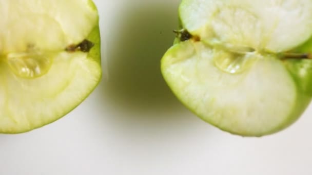 Two apples halfs falling down into the milk — Stock Video