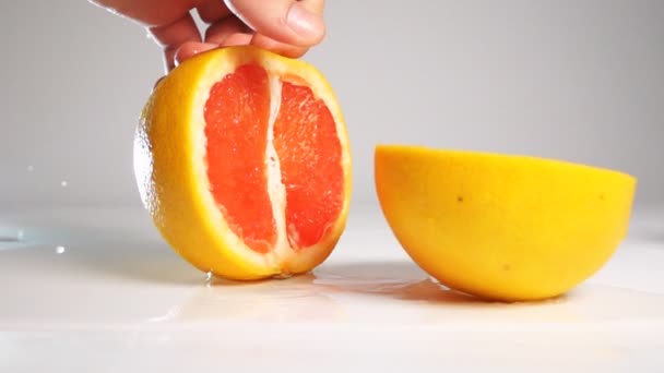 Разрезать грейпфрут на белой поверхности ножом — стоковое видео