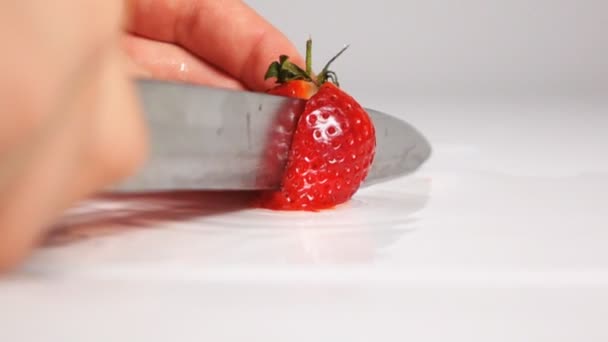 Cut strawberry on white surface by knife — Wideo stockowe