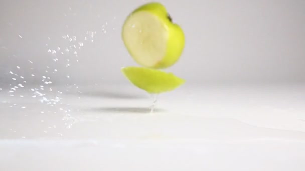 Sliced apple drop down on white surface — Stock Video