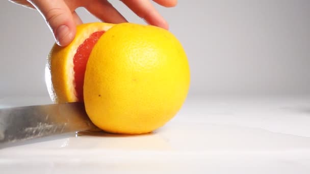 Cortar el pomelo sobre la superficie blanca con un cuchillo — Vídeos de Stock