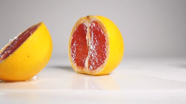 Грейпфрут розбивається на дві половинки на білій поверхні — стокове відео