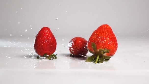 Strawberries drop on white wet surface — Stock Video