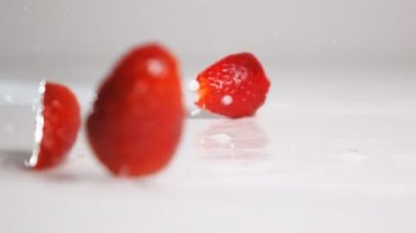 Dilimlenmiş çilek beyaz yüzeye düşer