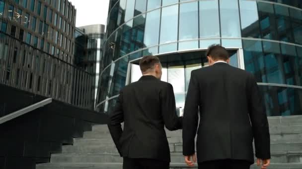 Два бизнесмена поднимаются по лестнице — стоковое видео