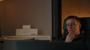 Kafkasyalı erkek laptop ekranının arkasında iş çözümünü düşünüyor