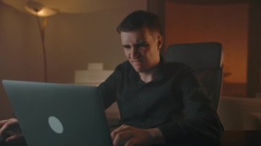 Erkek oyuncu, dairenin sıcak akşamında dizüstü bilgisayarla oynayarak raundu kazanıyor.