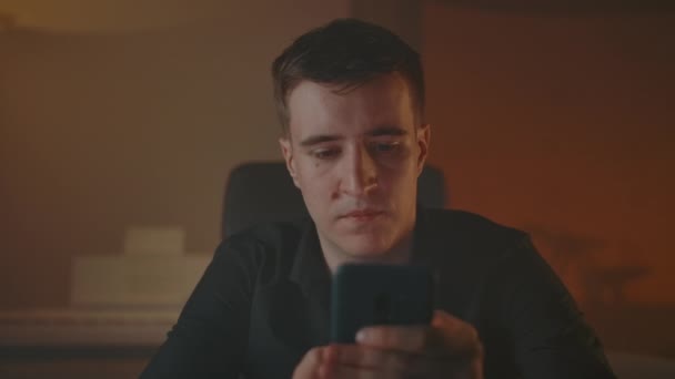 Άνθρωπος πληκτρολογώντας μηνύματα στο smartphone στο καπνιστό άνετο δωμάτιο βράδυ — Αρχείο Βίντεο