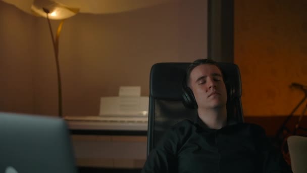 Καυκάσιος άνδρας χαλαρώνοντας στην πολυθρόνα στο άνετο σπίτι ακούγοντας μουσική. — Αρχείο Βίντεο