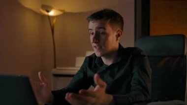 Adam kaskını takıyor ve evdeki dizüstü bilgisayarın arkasına gözlük takıyor.