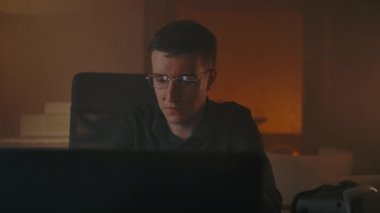 Gözlüklü, zeki, beyaz erkek. Ev içi konforlu bir evde dizüstü bilgisayarda çalışıyor.