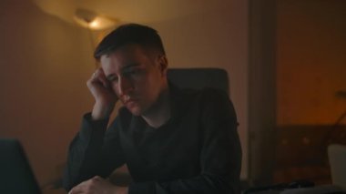 Uyuyan adam laptopun arkasında uyanıyor, evde çalışıyor..