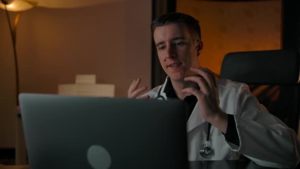 Läkaren talar om att behandla en patient genom ett online-konferenssamtal på en bärbar dator — Stockvideo