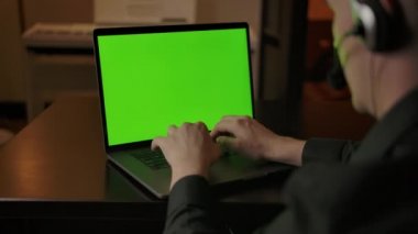 Evdeki çağrı merkezi çalışanı müşteriyle konuşuyor. Masada yeşil ekran laptop