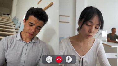 Bir adam çevrimiçi görüşme sırasında sıkılmış gibi görünürken diğer kişi arka planda takılıyor. Ayar parlak ve merdivenli asgari düzeyde..