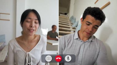 Bir adam iki kişiyle çevrimiçi görüşme yaparken sıkılmış görünüyor. O ilgisiz görünürken onlar fikirleri paylaşıyorlar. Arka planda bir merdiven ve ışık ayarı görünüyor..