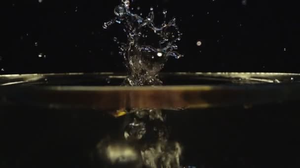 Halbe Zitrone auf Wasser mit Spritzer — Stockvideo