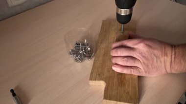 Elektrikli tornavida tahtaya vida sokuyor. Marangozluk işi. Mobilya montajı.
