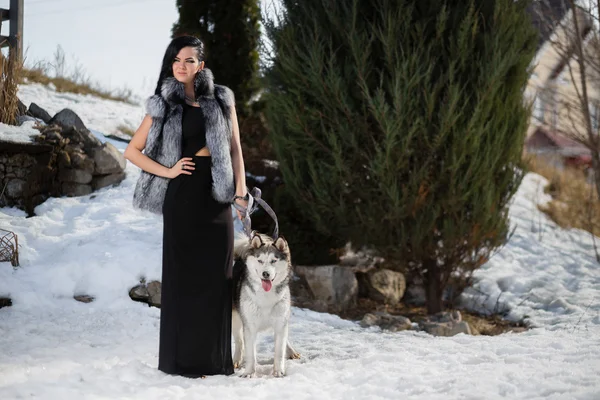 Femme sérieuse dans un chapeau de fourrure avec un chien Husky — Photo