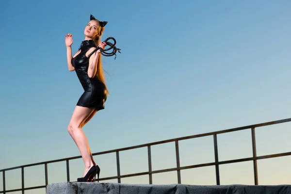 Женщина на крыше в костюме кошки с кнутом — стоковое фото