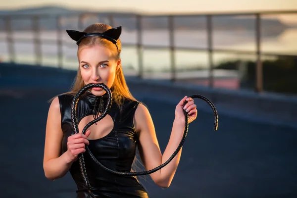 Kadın çatıda kedi kostümlü bir kamçı ile