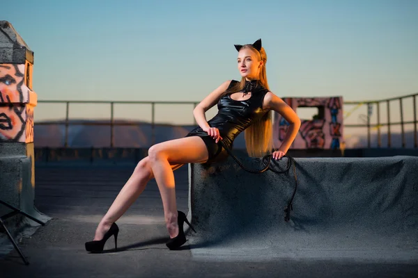 Kadın çatıda kedi kostümlü bir kamçı ile