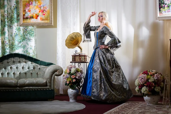 Дама в середньовічного плаття стоячи поряд з диваном — стокове фото