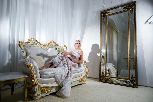 Κορίτσι σε ένα πολυτελές φόρεμα ξαπλωμένη στο καναπέ και καθρέφτες — Φωτογραφία Αρχείου