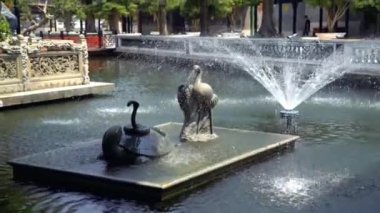 Parkta Feng Shui sembolleri olan bir çeşme. Kaplumbağa ve vincin üzerinde yatan bir yılan. Mutluluğu, iyi şansı ve her türlü talihsizlikten korunmayı sembolize ederler. Guangzhou Çin 'deki Banyo Parkı.