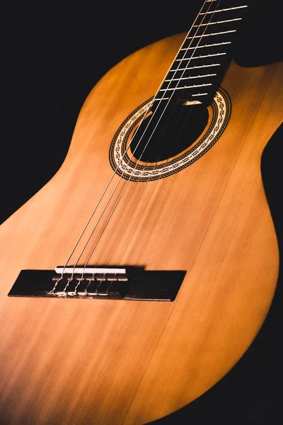 Klasik müzik severler için, koyu arkaplanda ön manzaralı ahşap bir akustik gitarın güzel yakın plan çizimi.