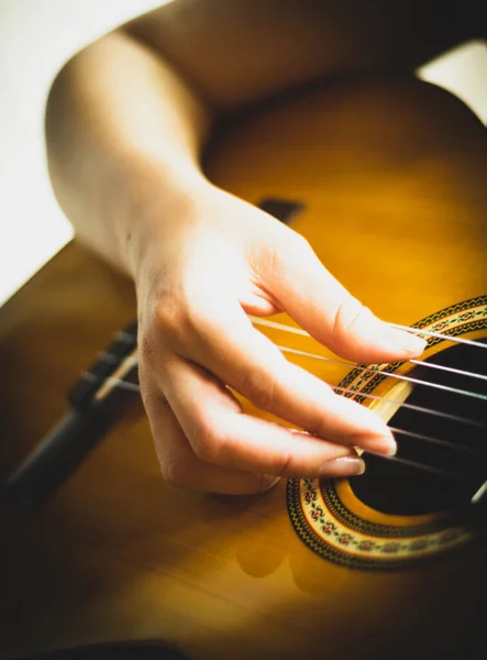 Beyaz bir arka planda doğaçlama yapan ve akustik gitar çalan bir kadının eli.
