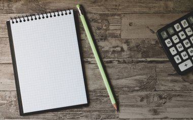  Tahta masa üzerinde kalem ve hesap makinesi olan beyaz sayfa günlüğü. Üst görünüm