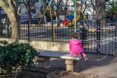 Nio mirando la plaza cerrada por la cuarentena yüzünden kapalı oyun parkına bakan bir çocuk.
