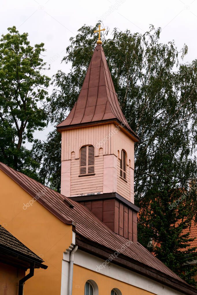 Church tower with a cross on the street of the small town of Cesis in Latvia